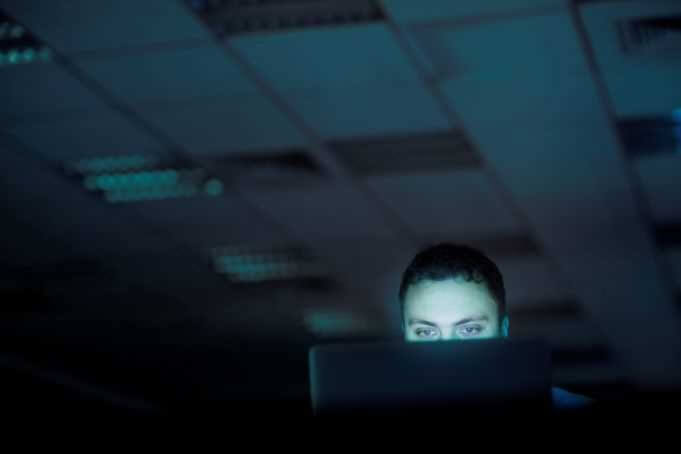 man looking at computer screen in a dark room